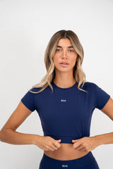 Žena u navy plavom Contour Fit crop topu i tajicama Être brenda tijekom vježbanja pilatesa - premium sportska odjeća za fitness