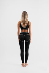 Être Noir et Blanc crne tajice i sportski grudnjak s bijelim prugama - stražnja strana, premium ženska sportska odjeća