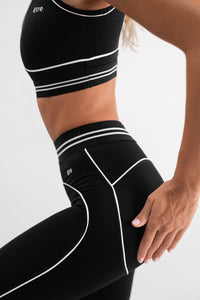 Detalj crnog Être Noir et Blanc seta tajice i top - bijele kontrastne pruge i šavovi, visoki struk, premium ženska sportska odjeća