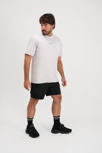 Muškarac u Être Active Light Gray svijetlo sivoj majici s malim logom, crne sportske kratke hlače i crne Être čarape s bijelim prugama - kompletni muški sportski outfit, bočni pogled, indoor studio fotografija, casual athleisure styling