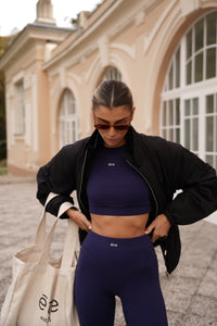 Navy plavi Contour Fit sportski set Être - tajice i crop top s logom, styling s bež tote bag torbom, outdoor lifestyle fotografija, premium ženska sportska odjeća